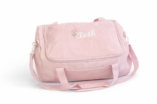 Pink duffel bag with 'Beth' embroidered on a white background