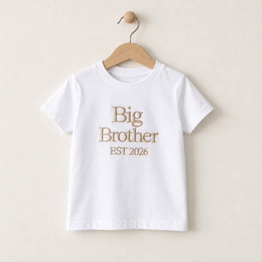White children’s T-shirt embroidered with Big Brother EST 2026 in beige thread