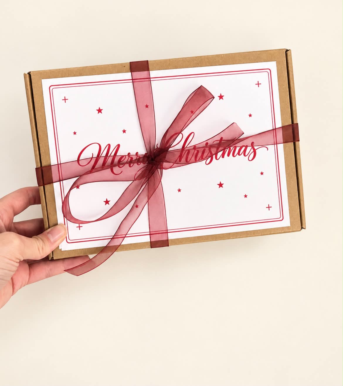 Christmas chocolate gift box tied with burgundy ribbon held in hand