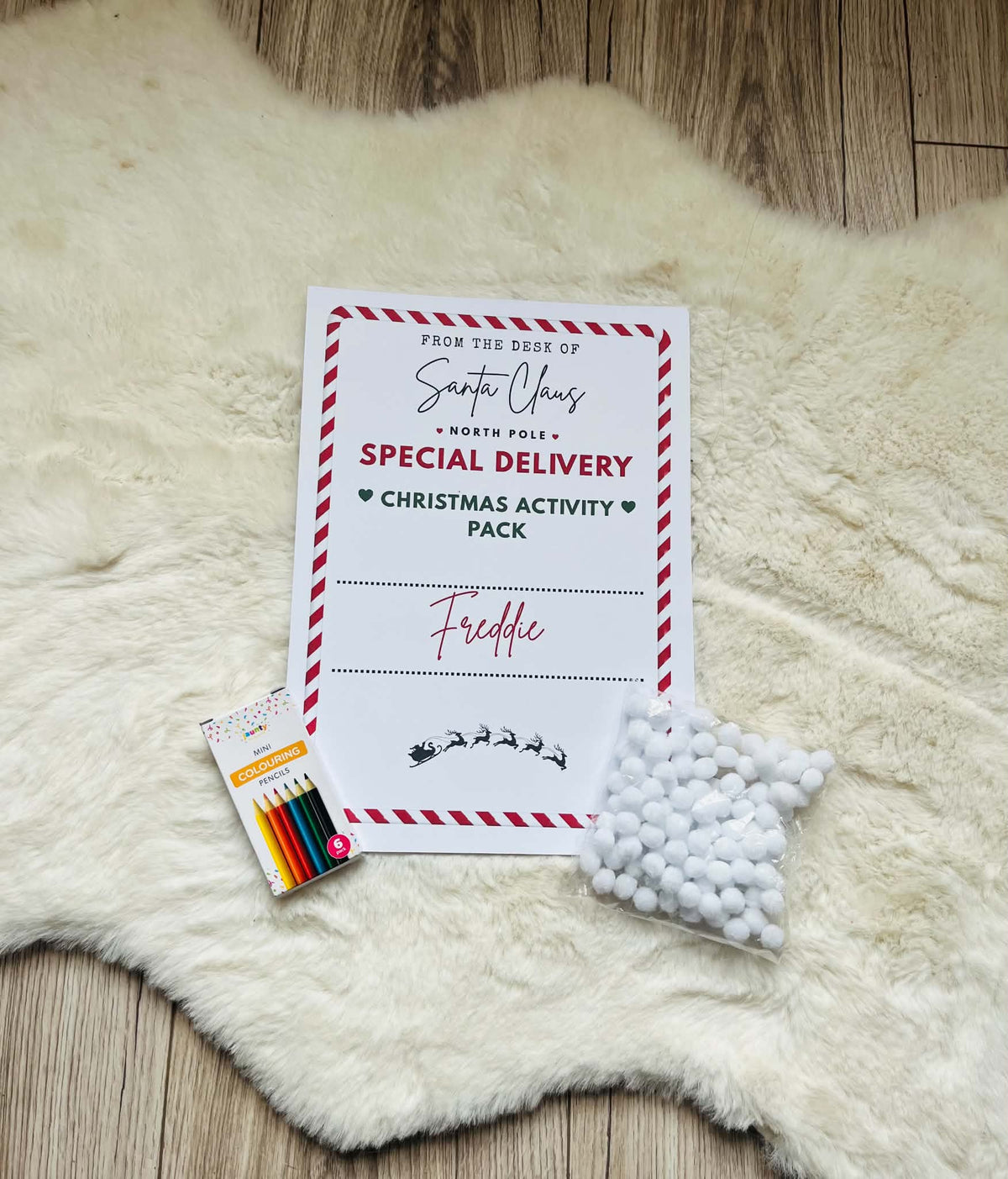 Personalised Christmas activity pack with Freddie name cover, colouring supplies and white Santa beard pom-poms