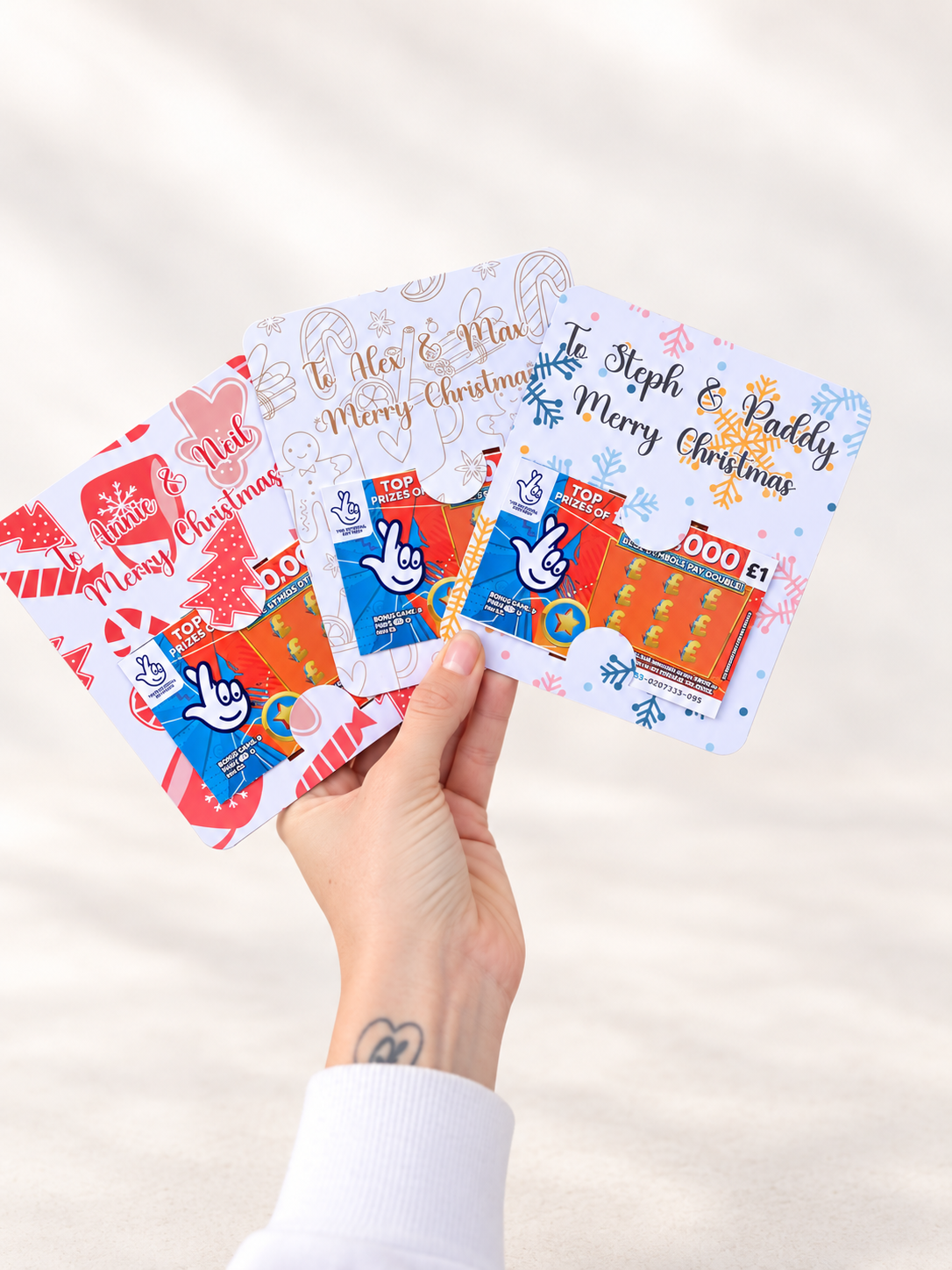 Four personalised Christmas scratch card holders with festive designs displayed against a clean neutral background