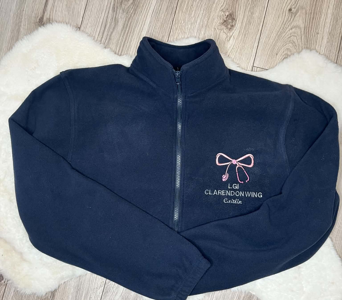 Navy fleece embroidered with a pink bow and stethoscope, LGI Clarendon Wing and Caitlin name